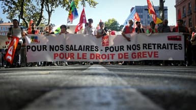 Des manifestants défilent derrière une banderole sur laquelle on peut lire "Pour nos salaires, pour nos retraites, pour le droit de grève" lors d'une manifestation à Toulouse, dans le sud-ouest de la France, le 18 octobre 2022