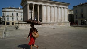 Une femme se protège du soleil avec une ombrelle dans une rue de Nîmes, le 19 juillet 2023 lors d'une vague de chaleur en France (photo d'illustration)