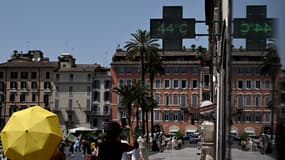 Des piétons marchent sous l'enseigne d'une pharmacie indiquant la température extérieure actuelle près de la fontaine Barcaccia devant la Place d'Espagne à Rome le 17 juillet 2023, lors d'une vague de chaleur en Italie.