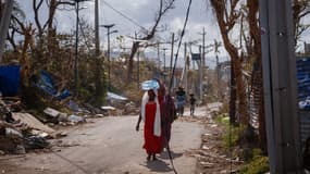 Une femme transporte de l'eau à Pamandzi, sur le territoire français de Mayotte, dans l'océan Indien, le 17 décembre 2024, après que le cyclone Chido a frappé l'archipel.