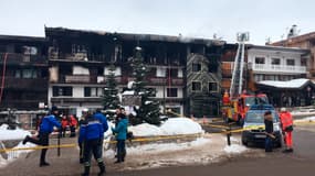 Des pompiers et des gendarmes se tiennent devant un bâtiment détruit par un incendie majeur qui a tué deux personnes, le 20 janvier 2019 dans la station de ski de Courchevel.