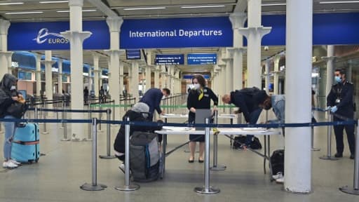 Des voyageurs équipés de masques de protection remplissent un formulaire au terminal de l'Eurostar de St Pancras, le 8 juin 2020 à Londres