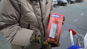 Des Ukrainiens présentent une lampe d'appoint qu'ils viennent d'acheter en prévention des coupures de courant, novembre 2024