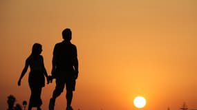 Deux personnes marchent sous le soleil couchant (image d'illustration)