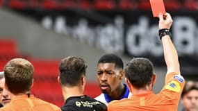 L'arbitre Ruddy Buquet adresse un carton rouge au défenseur du Paris Saint-Germain Presnel Kimpembe, durant la rencontre entre le PSG et le Stade rennais, le 9 mai 2021 à Rennes