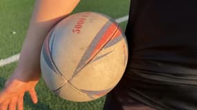 Un enfant tient un ballon de rugby à un entraînement