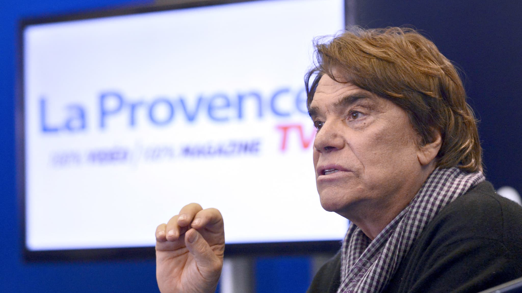 L'homme d'affaires français Bernard Tapie, lors d'un discours lors d'une conférence de presse le 12 mars 2014 à Marseille, dans le sud de la France, pour annoncer le lancement d'une web TV, une nouvelle branche du journal français "La Provence", qui proposera une émission intitulée "Tapie se met a table" dans laquelle l'homme d'affaires recevra chaque soir lors d'un dîner les cinq principaux candidats à la mairie de Marseille en mars 2014. (légende AFP) 