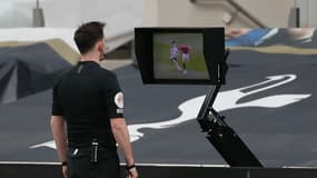 Un arbitre central de Premier League en pleine utilisation de l'assistance vidéo.