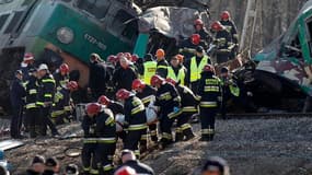 Secouristes évacuant un corps de la carcasse d'un wagon. Une collision entre deux trains de voyageurs a fait 16 morts et une soixantaine de blessés, samedi soir à Chalupki, dans le sud de la Pologne. /Photo prise le 4 mars 2012/REUTERS/Peter Andrews