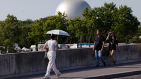 Une personne s'abrite du soleil sous un parasol près de la Seine à Paris le 21 juin 2025, lors d'une vague de chaleur