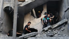 Des membres de la défense civile palestinienne et d'autres personnes transportent un enfant tué lors d'un bombardement israélien d'un bâtiment à Khan Yunis, dans le sud de la bande de Gaza, le 19 octobre 2023.