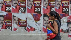 Une femme devant des affiches de campagne du président vénézuélien Nicolas Maduro, à Caracas le 19 mai 2018