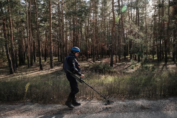 Un soldat ukrainien cherchant de potentielles mines sur une route en bordure de forêt près de la ville de Lyman, en Ukraine, en octobre 2022