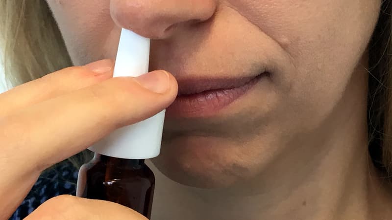 Une femme en train de mettre du spray nasal. 