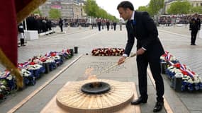 Le président Emmanuel Macron allume la flamme de la tombe du Soldat inconnu à l'Arc de Triomphe lors des cérémonies du 8 mai 1945, le 8 mai 2023 à Paris