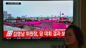 Une femme passe devant un écran diffusant des images de la parade donnée à Pyongyang en l'honneur de Kim Jong-Un. 
