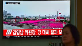 Une femme passe devant un écran diffusant des images de la parade donnée à Pyongyang en l'honneur de Kim Jong-Un. 