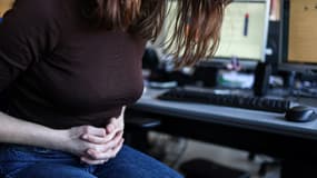 Une femme, assise à son bureau, souffre de douleurs menstruelles, le 1er mars 2023 à Toulouse.