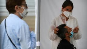 Une infirmière fait un prélèvement sur un patient dans un centre mobile de dépistage du coronavirus, sur la plage de Pentrez à Saint-Nic, dans l'ouest de la France le 12 août 2020