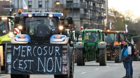 Un agriculteur conduit un tracteur avec une banderole sur laquelle on peut lire "Mercosur, c'est non !".