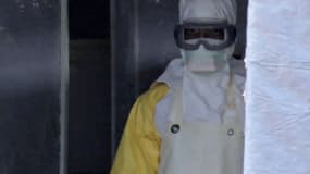 Un homme porte un masque et une combinaison de protection à l'entrée d'une tente médicale à Gueckedou, en Guinée.