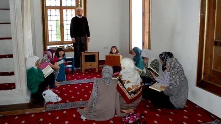 Un adjoint de l'imam dans la mosquée Sinan Pacha, au Kosovo, enseignant la prière à des femmes