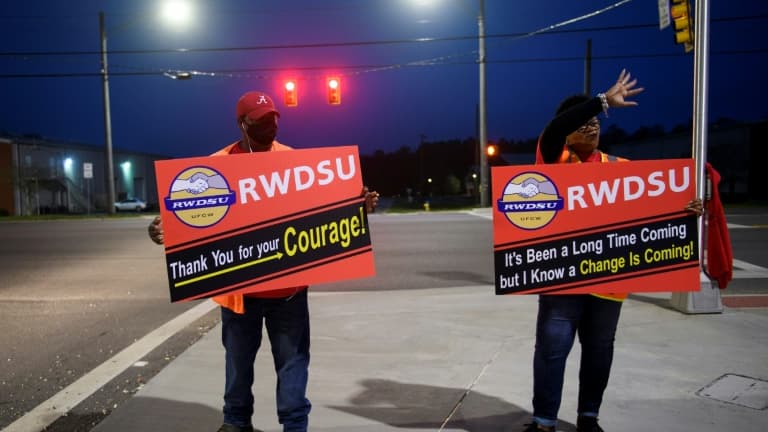 Des syndicalistes, pancartes à la main, saluent des automobilistes à l'entrée de l'entrepôt Amazon de Bessemer, le 27 mars 2021 en Alabama