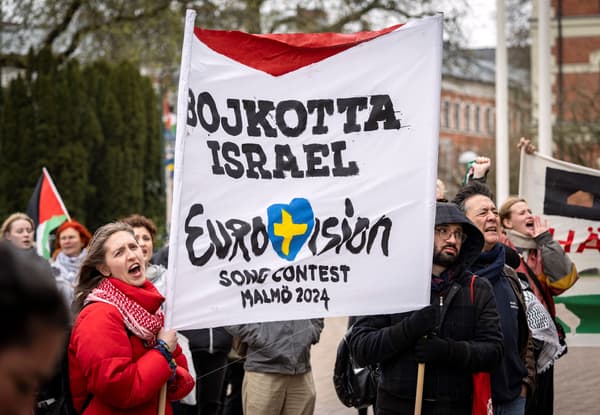 Des participants brandissent des drapeaux et des pancartes lors d'une manifestation devant l'hôtel de ville de Malmö, en Suède, le 10 avril 2024, à l'occasion de l'examen par le conseil municipal d'une proposition citoyenne visant à empêcher la participation d'Israël à l'Eurovision.