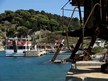 Des touristes débarquent d'un bateau amarré dans un port de l'île de Sazan, au large de l'Albanie, le 30 juillet 2024 (photo d'illustration).