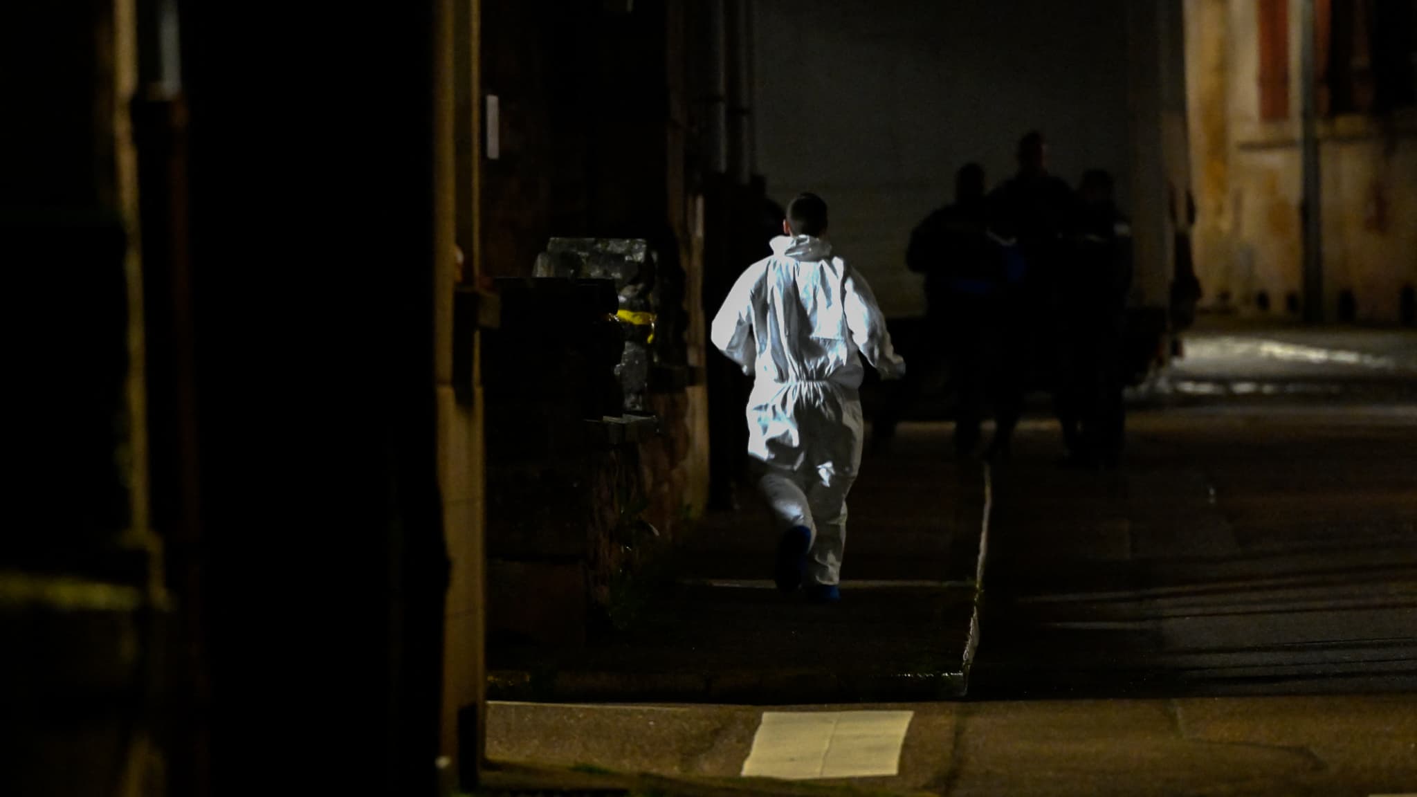 Un enquêteur de la police scientifique court près de la maison familiale de la fillette de cinq ans retrouvée morte dans un sac dans un appartement de Rambervillers, dans l'est de la France, le 25 avril 2023. 