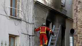 Un pompier inspecte l'immeuble incendié où trois personnes sont décédées à Stains (Seine-Saint-Denis)le 25 novembre 2023 