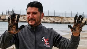 Hussein Hamza, un activiste environnemental libanais, montre ses mains couvertes de sable imbibé de goudron dans la réserve naturelle de Tyr, au sud du Liban, le 22 février 2021.