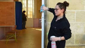 Une femme désinfecte la porte dans un bureau de vote de Bordeaux
