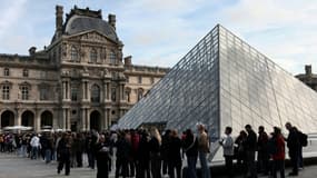 Des visiteurs font la queue devant la Pyramide du Louvre, conçue par l'architecte sino-américain Ieoh Ming Pei, et le musée du Louvre le jour de sa réouverture après un vol de bijoux, le 22 octobre 2025 à Paris