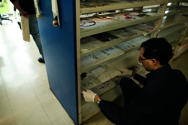 Des documents récupérés sont mis à sécher par un archiviste, aux archives de Paris Des documents récupérés sont mis à sécher par un archiviste, aux archives de Paris