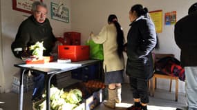 Un bénévole du Secours catholique (g.) distribue des colis de nourriture de la Banque Alimentaire, le 4 décembre 2009 à Saint-Eloy-les-Mines.