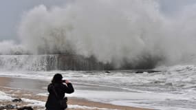 Un passant prend en photo une vague s'écroulant sur le littoral à Batz-sur-Mer, en Loire-Atlantique, le 31 décembre 2017. 