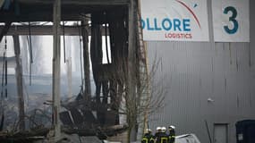 Des pompiers devant un bâtiment industriel loué par Bolloré Logistics endommagé par un incendie, le 17 janvier 2022 à Grand-Couronne, au sud de Rouen