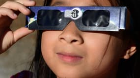 Une jeune fille portant des lunettes de protection lors d'une éclipse de soleil sur les monts San Gabriel, Los Angeles
