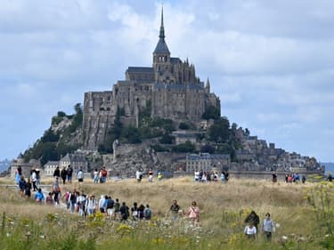 Des touristes marchent près du Mont-Saint-Michel, dans la Manche, le 25 juillet 2023