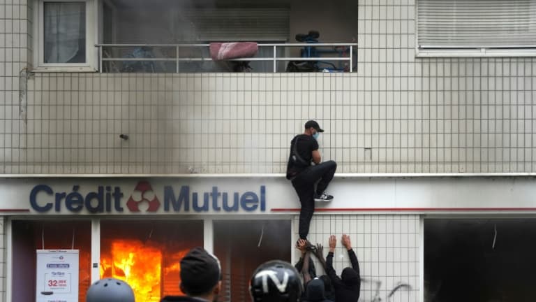 Un individu grimpe sur un bâtiment à l'issue d'une marche blanche en hommage à Nahel, le 29 juin 2023 à Nanterre, dans les Hauts-de-Seine