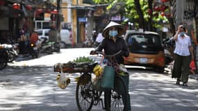 Une vendeuse de fruits circule avec son vélo dans les rues d'Hanoi, le 28 mai 2021 (PHOTO D'ILLUSTRATION)