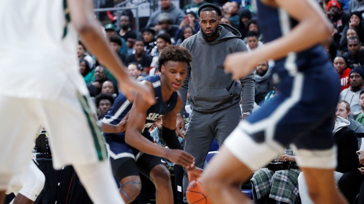 LeBron James (arrière-plan) observe son fils Bronny lors d'un match entre Sierra Canyon et St Vincent-St Mary, son ancien lycée, en décembre 2019 LeBron James (arrière-plan) observe son fils Bronny lors d'un match entre Sierra Canyon et St Vincent-St Mary, son ancien lycée, en décembre 2019