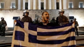 Manifestant opposé aux nouvelles mesures d'austérité devant le Parlement à Athènes. Le gouvernement grec a approuvé samedi la version définitive des mesures d'austérité réclamées par l'Union européenne et le FMI pour débloquer un plan d'aide de 130 millia