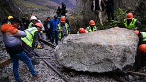 Des ouvriers tentent d'enlever une pierre placée par des émeutiers sur la voie ferrée pour bloquer le passage du train vers et depuis la citadelle inca du Machu Picchu à Ollantaytambo, au Pérou, le 17 décembre 2022. 