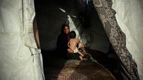 Reem Nasr tient son fils souffrant de malnutrition, Nafez, dans leur tente de fortune dans la région de Nuseirat, au centre de Gaza, le 4 octobre 2025.