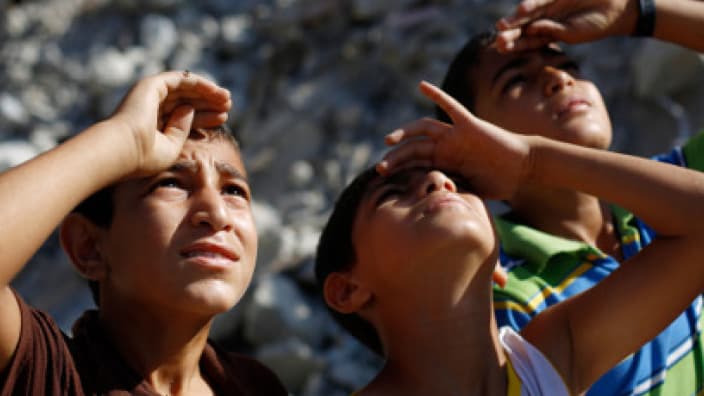 Des enfants palestiniens en train d'observer un avion de l'armée israélienne dans le nord de la bande de Gaza, le 4 août