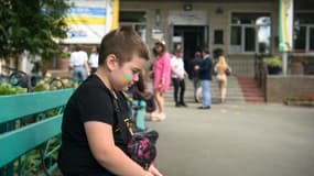 Un enfant assis devant une école lors d'une cérémonie d'ouverture après la reconstruction de l'établissement à la veille de la rentrée scolaire à Boutcha, en Ukraine, le 31 août 2022. 