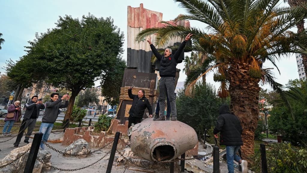 Des personnes se tiennent au sommet d'une statue déboulonnée de l'ex-président syrien Hafez al-Assad à Damas, le 8 décembre 2024.