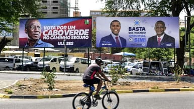 Un cyciste passe devant des panneaux électoraux, à la veille des élections législatives au Cap-Vert, le 17 avril 2021.